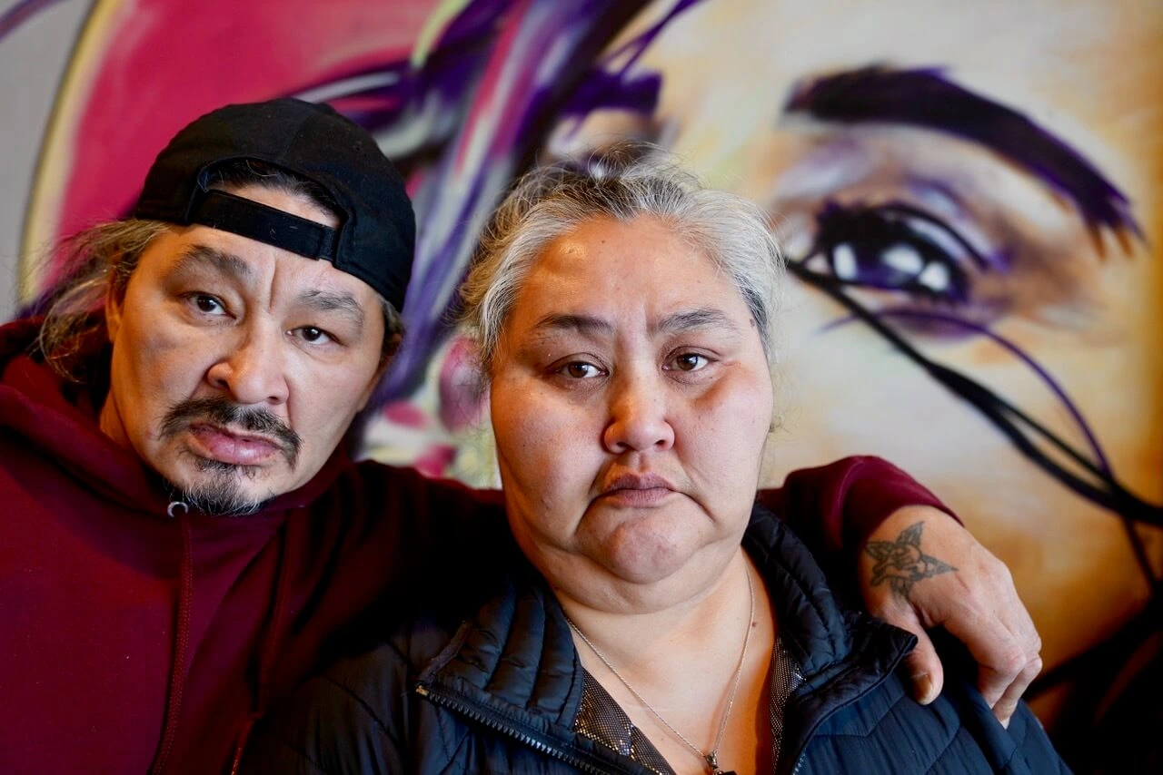 A Native Alaskan man and woman sitting together in front of a painting